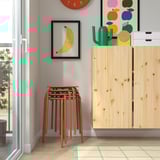 Sgabelli in legno impilati vicino all'armadio con decorazioni colorate.