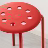 Sgabello moderno rosso vivo con fori circolari nella seduta, robuste gambe in metallo, design minimalista.