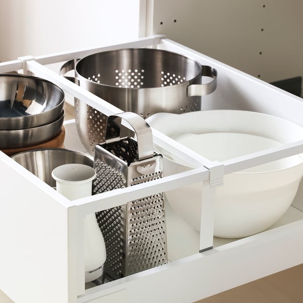 Cassetto della cucina aperto che mostra gli utensili organizzati, tra cui pentole, grattugie e ciotole, sottolineando un facile accesso e conservazione.