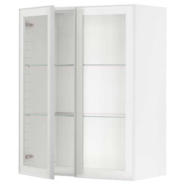 Si vede un mobile da cucina METOD bianco con ante in vetro e ripiani in vetro trasparente incorniciati da metallo, che si adatta perfettamente ai moderni design della cucina.
