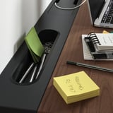 Una scrivania regolabile in altezza, MITTZON, contiene un dispositivo digitale, quaderni e articoli di cancelleria, sottolineandone l'organizzazione.