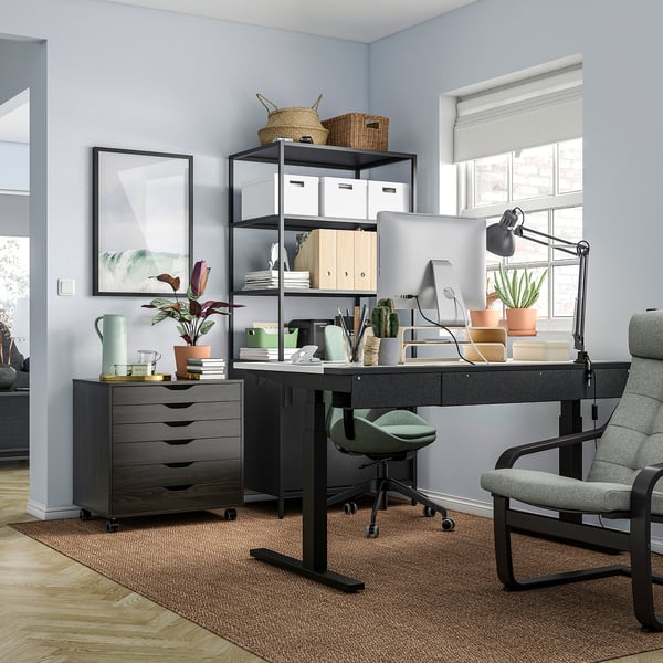 Moderno ufficio domestico con scrivania nera MITTZON sit/stand, sedia grigia e oggetti decorativi.