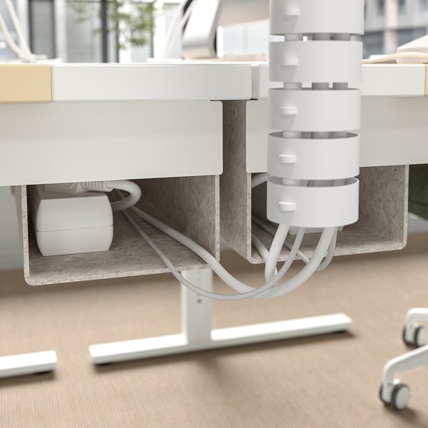 L'immagine mostra una scrivania sit-stand con doppio motore per la regolazione dell'altezza, dotata di vassoio per la gestione dei cavi e ganci per gli accessori.