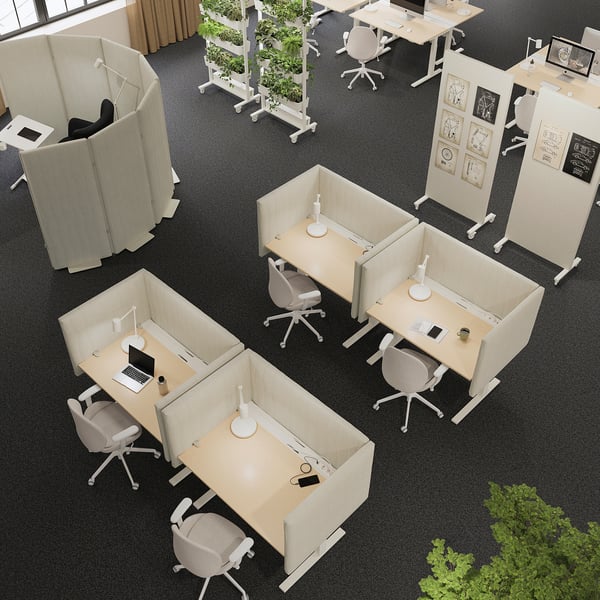 Ufficio moderno con scrivanie e sedie bianche MITTZON, alcune con piante, divise da paraventi beige. Le scrivanie sono rettangolari con altezze regolabili.