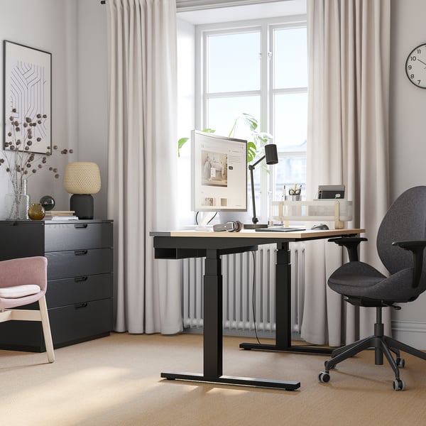 Home office: scrivania nera MITTZON, sedia grigia, tende bianche, pavimento in legno chiaro, grande finestra, parete grigia.