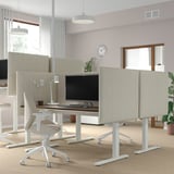 Ufficio moderno con scrivanie sit/stand MITTZON, monitor, sedie, schermi acustici e piante.