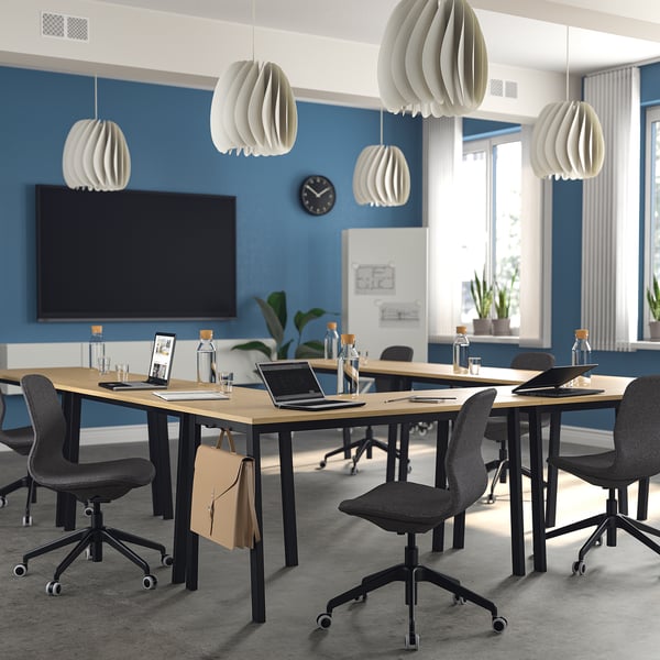 Moderna sala conferenze con tavoli MITTZON, sedie grigie, pareti blu e un grande schermo.