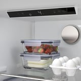 All'interno di un moderno frigorifero, fragole e formaggio sono conservati ordinatamente in contenitori. Il display digitale del frigorifero mostra la temperatura a 4°c.