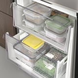 Frigorifero aperto con ripiani regolabili, contenitori trasparenti che contengono vari alimenti.