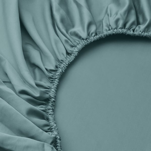 Morbido lenzuolo con angoli blu-verde con design arricciato, che mette in mostra una trama liscia del tessuto e una lavorazione artigianale di qualità.