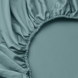 Morbido lenzuolo con angoli blu-verde con design arricciato, che mette in mostra una trama liscia del tessuto e una lavorazione artigianale di qualità.