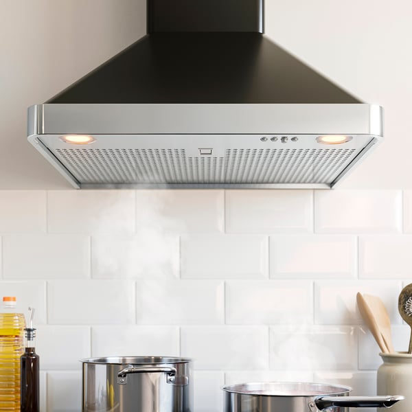 Cucina moderna con cappa in acciaio inox NILSBYN , luci accese e pentole metalliche.