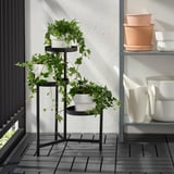 Il supporto per piante a tre livelli mostra piante verdi su un balcone, utilizzando lo spazio verticale in modo efficiente.