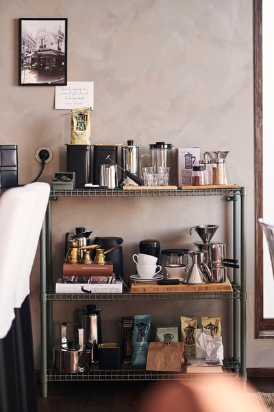 Una rastrelliera in metallo verde a tre ripiani, robusta e dal look industriale, perfetta per le varie esigenze di stoccaggio.