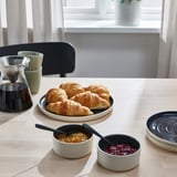 Tavolo da colazione apparecchiato con brioches, marmellate e caffè.