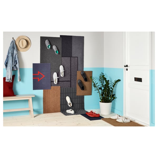 Sala luminosa con porta bianca, parete blu, stuoie colorate, panca con cappello e cappotto e una pianta in vaso.