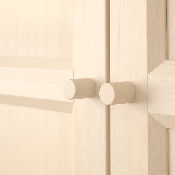 Mobiletto in legno chiaro con eleganti maniglie cilindriche. Consistenza liscia e ben levigata. La maniglia orizzontale si estende al centro, due verticali sul lato destro.
