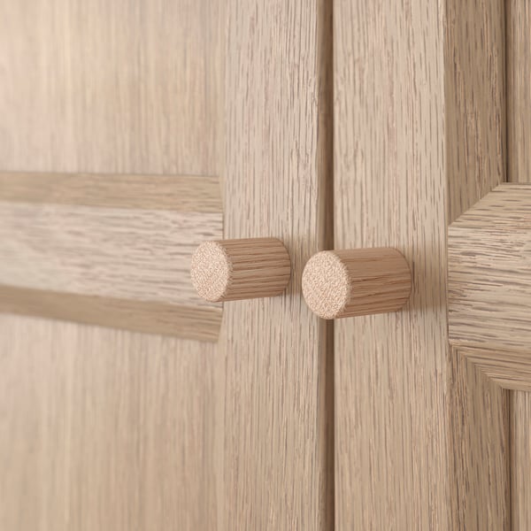 Pomelli dell'armadio in legno: due pomelli rotondi in legno naturale sulla porta in legno chiaro, che mostrano un design di qualità.