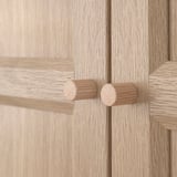 Pomelli dell'armadio in legno: due pomelli rotondi in legno naturale sulla porta in legno chiaro, che mostrano un design di qualità.