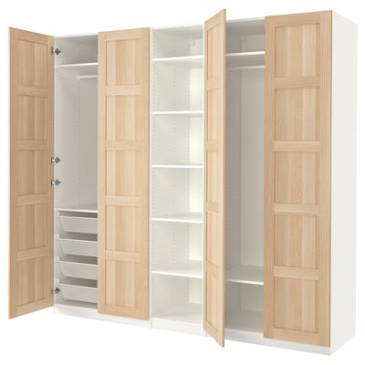 Questa immagine mostra un armadio ikea PAX in bianco e finitura legno chiaro. Quattro ante aperte, due ripiani e cestelli in rete estraibili.
