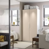 Camera da letto minimalista con ampio armadio, poltrona, tavolino, libri e tende trasparenti.
