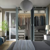 Armadio aperto con vestiti, cassetti e illuminazione, mostrato in una camera da letto.
