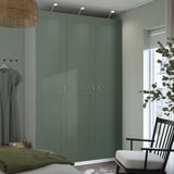 Camera da letto moderna con armadio PAX grigio alto, lampada a sospensione in vimini, sedia e pianta.