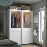 Camera da letto moderna con grande armadio PAX bianco, porte scorrevoli in vetro e vestiti puliti.