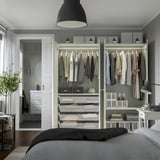 Camera da letto moderna con armadio a muro, lampada a sospensione, letto e bagno con doccia.
