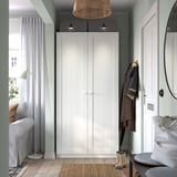 Ingresso moderno con alto armadio PAX bianco, due porte, luci e specchio, accanto al divano e alla porta grigi.