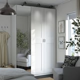 Camera da letto moderna con grande armadio PAX bianco, porte scorrevoli a specchio, lampada a sospensione e sedia. Include cestello in rete e piedini regolabili.
