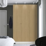 Camera da letto moderna con grande armadio in legno PAX, letto bianco e indumento blu.