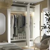 Armadio aperto con vestiti, mensole e scatole portaoggetti. Illuminazione integrata, piedini regolabili e cerniere a chiusura ammortizzata a vista.