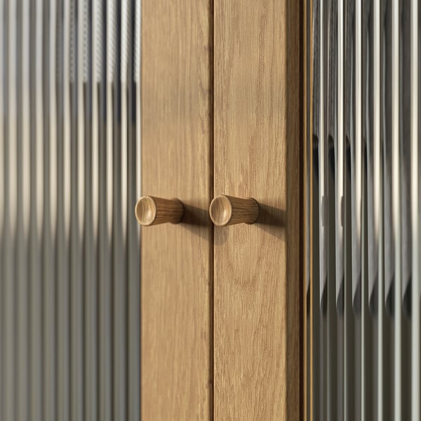 Maniglie delle porte in legno dell'armadio PAX. Le maniglie sono marrone chiaro, cilindriche e posizionate orizzontalmente su una porta beige con venature del legno.