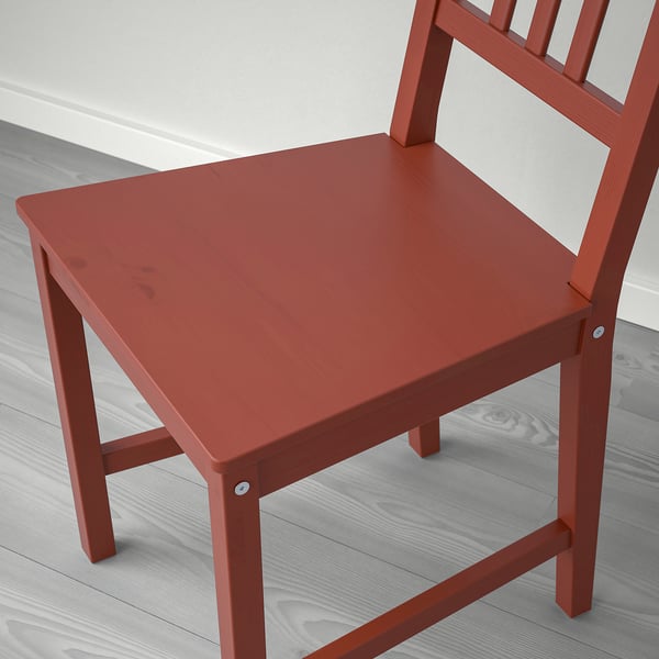 Sedia in legno rosso con doghe verticali su pavimento chiaro.