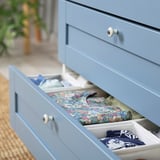 Cassettiera PLATSA azzurra con vestiti organizzati; Abito floreale e sciarpe piegate in scomparti.