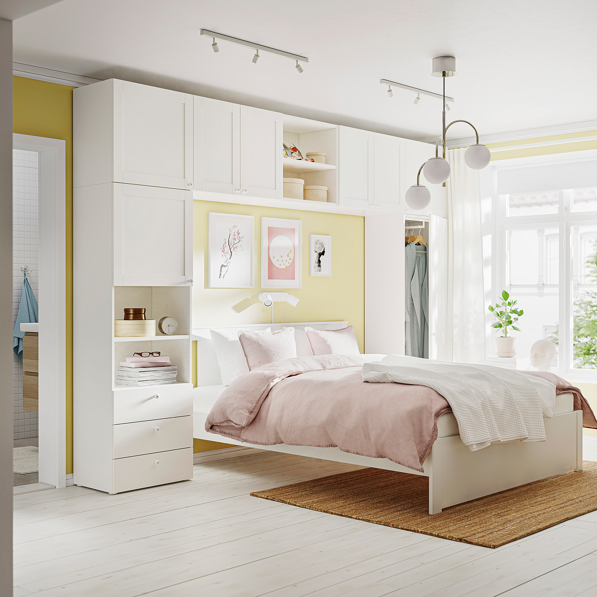 Camera da letto moderna e minimalista con mobili contenitori PLATSA bianchi, un letto con coperta rosa e tre lampadine sospese.