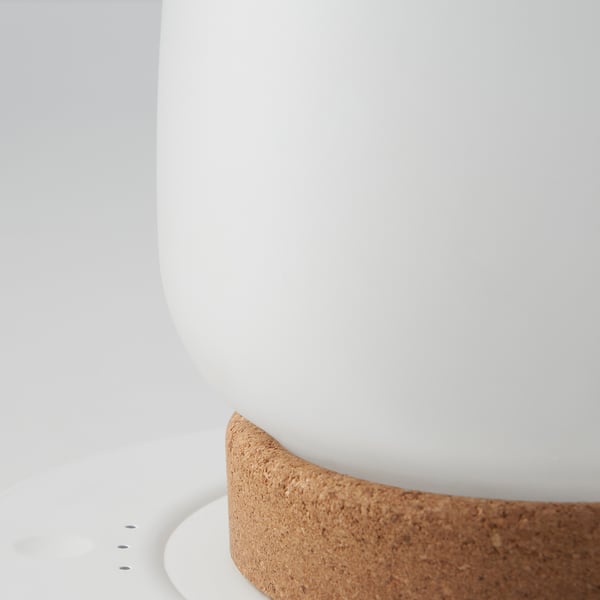 Primo piano di una lampada elegante e moderna con cupola in vetro liscio e base in sughero testurizzato, che mette in mostra materiali e design di alta qualità.