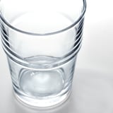 Tazza di vetro trasparente, piccola quantità d'acqua, base spessa, impilata ordinatamente.