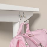 Una scrivania bianca regolabile con una borsa rosa agganciata su di essa.