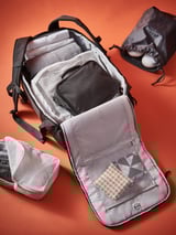 Borsa RENSARE bianca su sfondo rosso, che mostra scomparti organizzati in rete con vestiti e accessori.