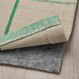 Un tappeto color crema a quadri verdi posato su una parte inferiore in feltro grigio, ideale per le zone pranzo.