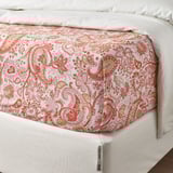 Letto con lenzuolo piatto fantasia paisley floreale, dettaglio dell'orlo in mostra e morbido misto tessuto.