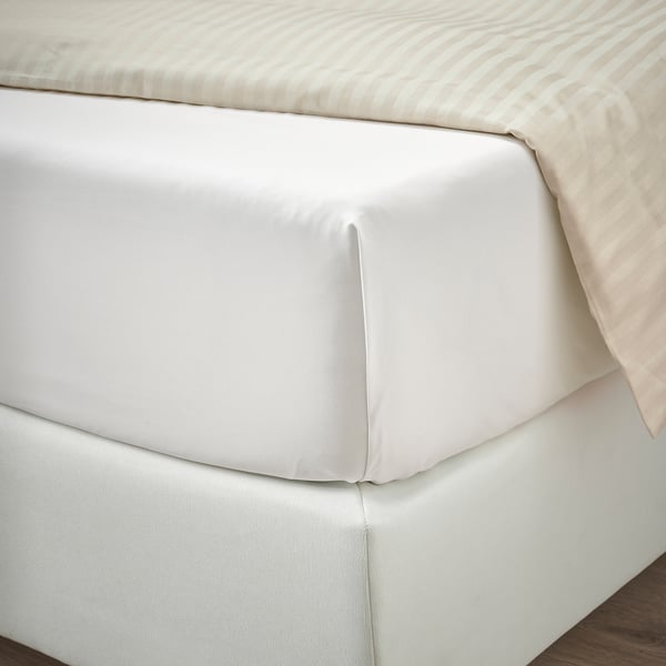 Lenzuola bianche fresche realizzate con cura su un materasso, in percalle di cotone liscio e di alta qualità con una finitura fresca e asciutta.