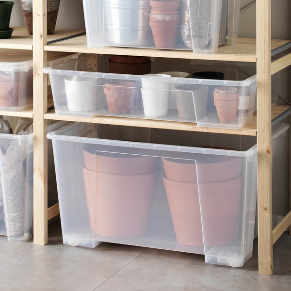 Contenitori di plastica con ruote, che contengono fioriere rosa, il cestino più grande ne ha due grandi.