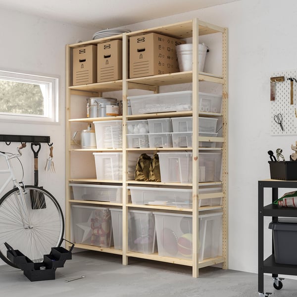 Scaffali per garage con scatole di plastica trasparente di varie dimensioni, contenenti provviste. La bici si appoggia al muro. Carrello nero accanto.