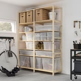 Scaffali per garage con scatole di plastica trasparente di varie dimensioni, contenenti provviste. La bici si appoggia al muro. Carrello nero accanto.
