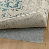 Tappeto decorativo con un design consumato, che mostra una lavorazione artigianale di qualità, posizionato su un pavimento in legno.