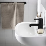 Lavandino da bagno moderno con rubinetto nero, sapone, portaspazzolino.