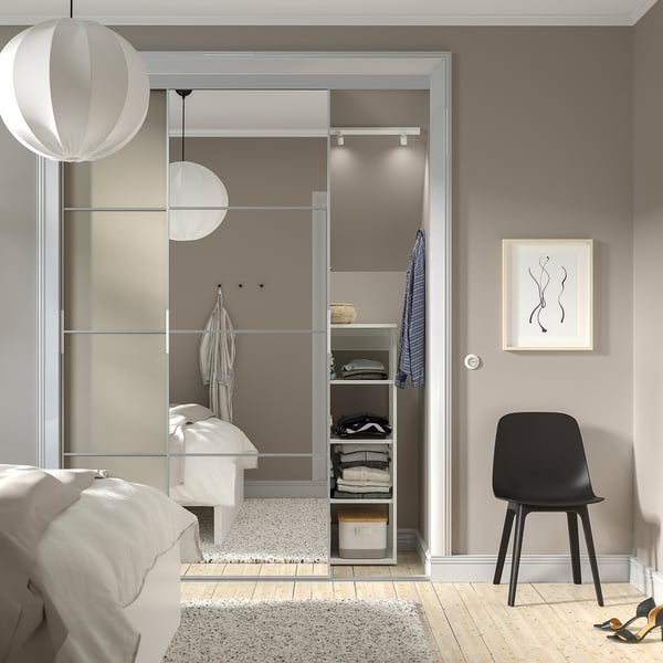 Camera da letto moderna con ampio armadio a specchio SKYTTA, luci soffuse e letto.